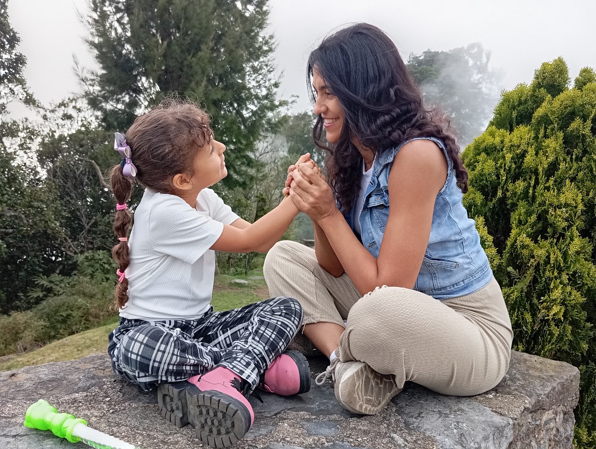 Lisseth tomada de la mano de su hija, sonriendo al aire libre
